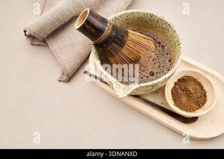 Poudre Hojicha avec de l'eau chaude fouettée dans un bol en céramique Banque D'Images
