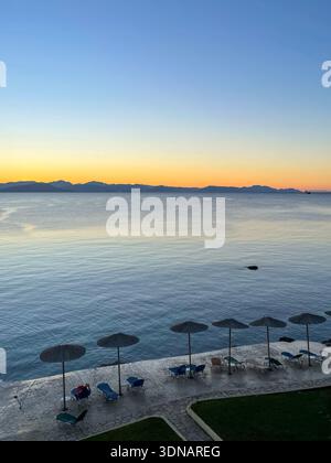 Magnifique lever de soleil sur la mer avec parasols et montagnes Banque D'Images