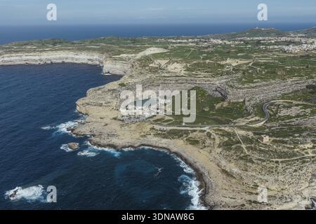 Vue aérienne des falaises accidentées embrassant les eaux turquoises de la mer intérieure près de la baie de Dwejra, une tapisserie de textures et de tons, San Lawrenz, Malte. Banque D'Images