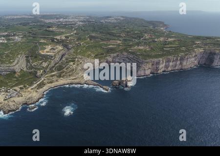 Vue aérienne des falaises escarpées embrassant la mer d'un bleu profond à Dwejra Bay, une tapisserie de textures et de tons, San Lawrenz, Malte. Banque D'Images