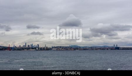 Istanbul, Turquie - 9 octobre 2025 : la ligne d'horizon d'Istanbul à travers le Bosphore. Des tours éloignées et des grues industrielles bordent le front de mer. Banque D'Images