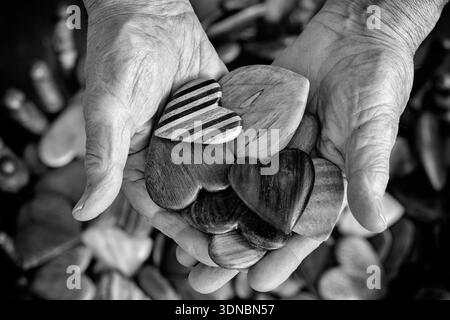 Mains de l'artiste Tommy Simpson tenant ses coeurs en bois faits à la main - Asheville, Caroline du Nord, USA [B&W image] Banque D'Images