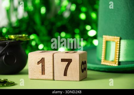 Composition de la St Patricks Day avec des blocs de calendrier en bois montrant le numéro dix-sept, chapeau vert, pièces de monnaie et décorations festives sur fond vert. Banque D'Images