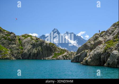 France, haute Savoie, réserve naturelle des aiguilles rouges, deux randonneurs au bord du lac Blanc, avec un parapente dans le ciel, en arrière-plan, l'aiguille du Chardonnet (3824 m) et l'aiguille d'Argentière (3901 m) Banque D'Images