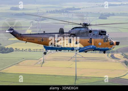 Cette image montre un hélicoptère Westland WS-61 Sea King Mk41 de la marine allemande, immatriculé 8958, numéro de série WA762, exploité par la Bundeswehr, en vol air-air avec une vue rapprochée du poste de pilotage et du pilote. Dérivé du Sikorsky S-61, le Sea King Mk41 est un hélicoptère maritime bimoteur propulsé par deux turbomoteurs General Electric T58. L'avion est équipé d'un rotor principal, d'un rotor de queue, d'un fuselage, d'un train d'atterrissage et d'une livrée commémorative marquant son service de 1972 à 2024. Banque D'Images