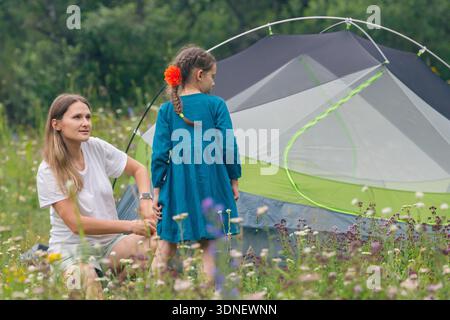 Une mère et sa fille profitent d'un voyage de camping ensemble dans une belle prairie panoramique entourée par la nature Banque D'Images