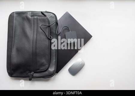 Portefeuille noir d'où vient un mini ordinateur portable avec une souris pour travailler en dehors du bureau. Banque D'Images