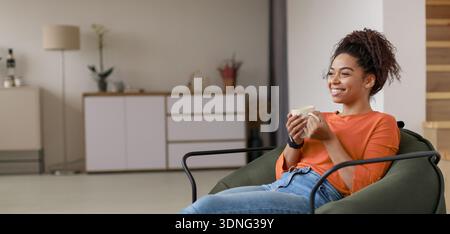 Femme aime la boisson chaude tout en se relaxant dans le salon dans la lumière de l'après-midi Banque D'Images