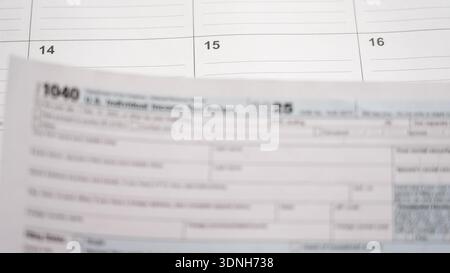 Nous préparer le formulaire d'impôt sur le revenu des particuliers 1040 pour 2025, en respectant la date limite du 15 avril sur un fond de calendrier Banque D'Images