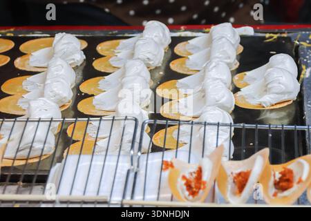 Crêpes croustillantes thaïlandaises Khanom Buang avec crème épaisse et garniture de noix de coco. Visuel authentique de Street food pour le voyage, la culture et le marketing culinaire. Banque D'Images