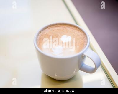 Cappuccino avec latte art en forme de cœur, gros plan sur une tasse de café, boisson chaleureuse du matin au café Banque D'Images