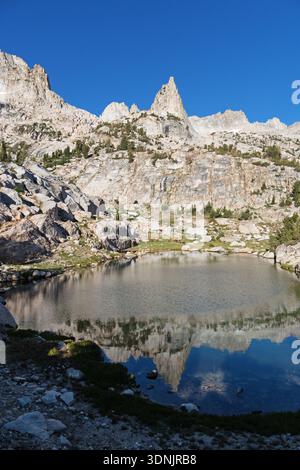 La flèche rocheuse des montagnes de la Sierra Nevada dans la chaîne des dents de scie se reflète dans un petit lac Banque D'Images