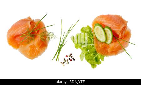 Tranches de filet de poisson de saumon salé fumé avec des légumes, des épices et des herbes volantes tombant isolé sur fond blanc. Collecte d'aliments sains. Banque D'Images