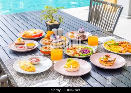 Assortiment de brunch sur une table extérieure au bord de la piscine, y compris des pâtisseries, Banque D'Images