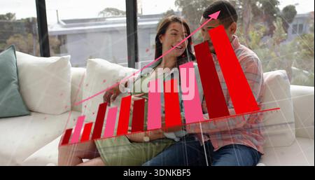 Assis deux femmes sur le canapé à la maison, partenaire enceinte portant une robe verte, tenant la tablette, graphique 3D. Banque D'Images
