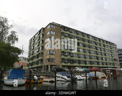 Copenhague, Danemark-19 septembre 2025 : hommes non identifiés marchant par des bateaux amarrés et Green Old Apartment Building Banque D'Images