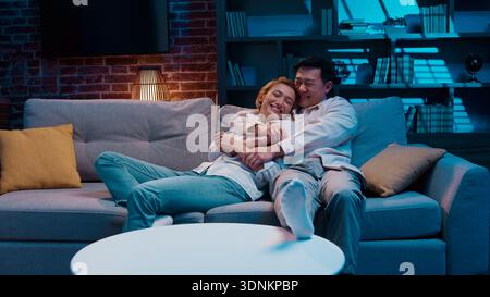 Couple multiracial homme asiatique femme caucasienne en cours de saut tombant sur la course du canapé dans le salon saut tomber sur le nouveau canapé confortable famille multiethnique Banque D'Images