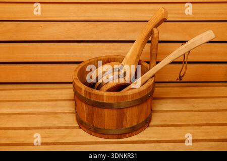 Seau de sauna en bois avec cuillère sur le banc.détail intérieur traditionnel du sauna finlandais. Banque D'Images