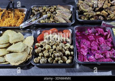 Un large choix d'aliments préparés sur des plateaux et dans des casseroles métalliques – carottes cuites et transformées, pommes de terre, côtes d'agneau, côtelettes, tartes, champignons, poivre rouge Banque D'Images