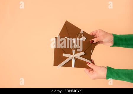 femme tenant deux enveloppes cadeaux dans les mains sur fond beige Banque D'Images