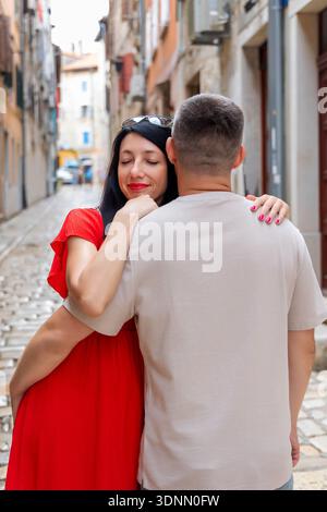 Couple aimant embrassant dans l'allée européenne. Femme heureuse embrassant son partenaire dans un câlin chaleureux dans une rue pavée dans une vieille ville européenne pittoresque. Banque D'Images