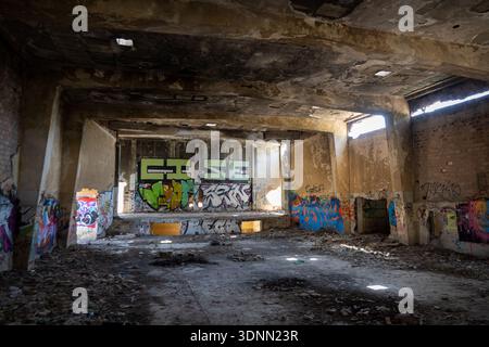 Vue intérieure d'un bâtiment abandonné avec de grandes lettres graffiti et un plafond en béton endommagé à la base aérienne de San Pablo, Espagne. Banque D'Images