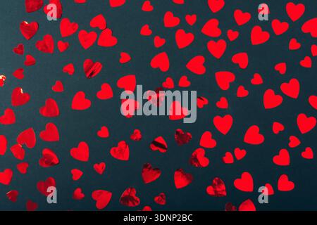 Cœurs de papier rouge dispersés sur fond noir. Concept de la Saint-Valentin. Vue de dessus, pose à plat. Banque D'Images