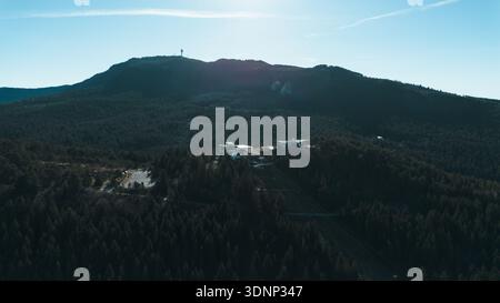 Vue aérienne de la station de téléphérique de Sarajevo entourée d'une forêt dense de pins et de crêtes montagneuses. Les infrastructures modernes se marient avec la nature, montrant urbain Banque D'Images