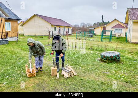 L'homme et la femme chaudement habillés ont fendu des bûches de bois de chauffage en morceaux allumés pour poêle à bois Banque D'Images