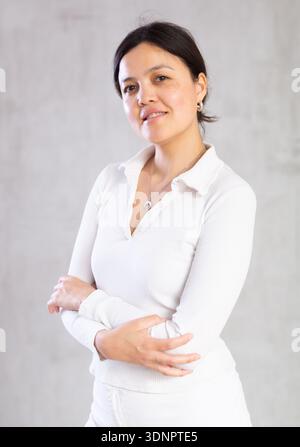 Jeune femme mince en vêtements légers et décontractés pose avec les bras croisés sur la poitrine. Banque D'Images