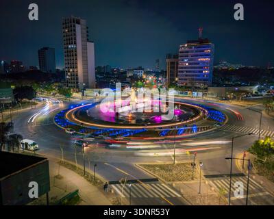 Vue aérienne de nuit longue exposition du rond-point la Minerva à Guadalajara, Jalisco, Mexique. Fontaine illuminée, sentiers de feux de circulation, horizon urbain et Banque D'Images