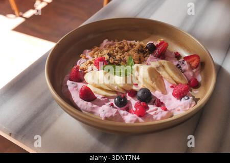 Bol de yaourt aux baies avec fruits et granola sur une table Banque D'Images