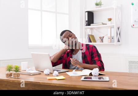 Homme d'affaires noir surmené dans un bureau décontracté, travailler avec un ordinateur portable Banque D'Images