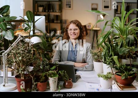 Portrait d'une femme confiante souriante tout en travaillant dans Biophilic Office Banque D'Images