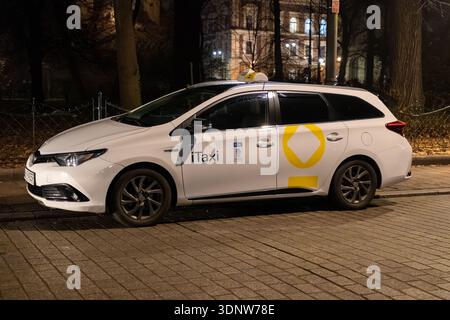 Cracovie, Pologne - 30 novembre 2025 : un taxi de station blanc visible de marque iTaxi, affichant les détails de la ville de Cracovie, stationné sur une rue urbaine pavée sombre Banque D'Images