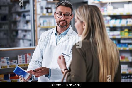 Homme mature, chimiste et aidant le client avec des médicaments pour la recommandation de pharmacie. Personne masculine, pharmacien ou femme consultante avec boîte pour médical Banque D'Images