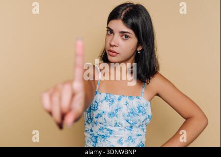 Une jeune femme se tient confiante avec son doigt levé, communiquant un sentiment d'importance. Banque D'Images