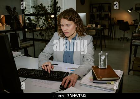 Jeune femme travaillant à l'ordinateur dans un environnement de bureau moderne Banque D'Images