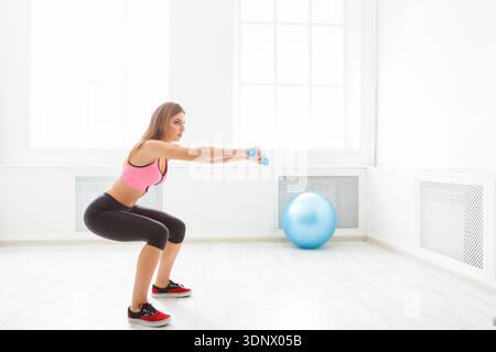 Jeune belle femme en vêtements de sport faisant squat Banque D'Images