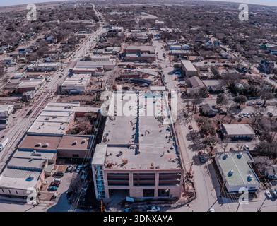 Vue aérienne de bâtiments baignés de soleil projetant de longues ombres le long des rues de la ville, mélangeant textures urbaines et éléments naturels, Frisco, Texas, United Banque D'Images