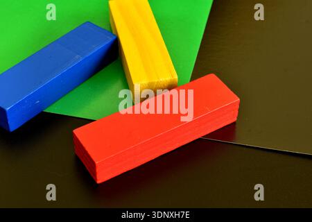 Trois blocs de bois du jeu de société Jenga, peints en bleu, jaune et rouge. Banque D'Images