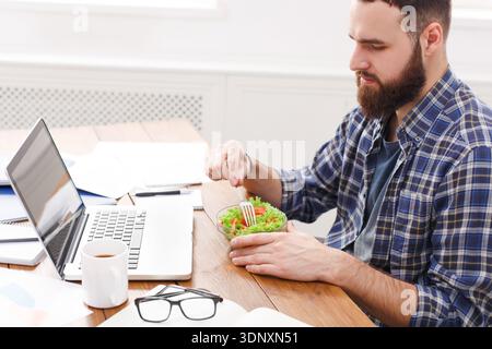 L'homme a un déjeuner d'affaires sain dans un intérieur de bureau moderne. Jeune bel homme d'affaires au lieu de travail Banque D'Images