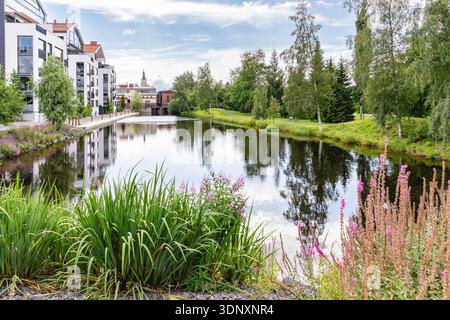 Oulu est la capitale européenne de la culture 2026 en Finlande. Beau paysage urbain, un canal avec des plantes et un parc de la ville Ainolanpuisto sur la droite. Banque D'Images