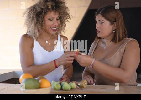 Deux femmes heureuses partagent un moment d'amitié franc, profitant d'une collation saine lors d'un déjeuner. Cette illustration de style de vie représente les loisirs et la joie parmi f Banque D'Images