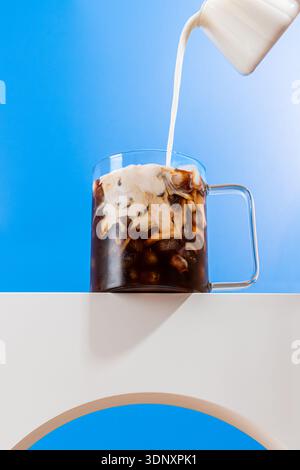 Un cliché dynamique capturant le lait crémeux versé dans un espresso glacé rafraîchissant, créant un magnifique effet tourbillonnant. Parfait pour un café sur le thème l Banque D'Images