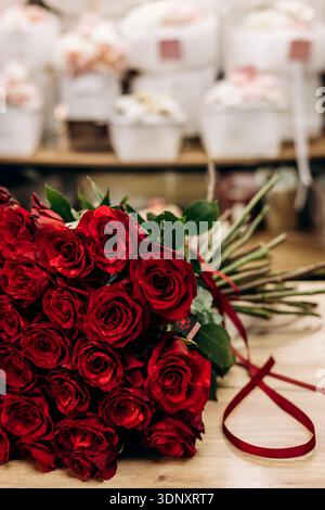 Un bouquet vibrant de roses rouges élégamment arrangé dans une boutique de fleuriste, mettant en valeur la beauté intemporelle et le romantisme. Parfait pour les occasions spéciales ou Heartfel Banque D'Images