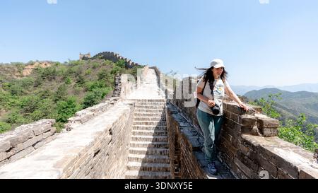 Un voyageur explore la section Jinshanling de la Grande Muraille de Chine, une partie restaurée située près de Pékin, sous un ciel bleu clair avec plus de verdure Banque D'Images
