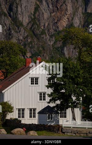Photo panoramique d'une maison traditionnelle en bois blanc nichée au milieu des spectaculaires falaises rocheuses des îles Lofoten en Norvège, capturant l'harmonie de Ar Banque D'Images