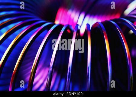 Spirales métalliques aux couleurs vives créant des formes abstraites avec éclairage au néon. La perspective gros plan met en évidence la torsion et la courbure par rapport à un Banque D'Images