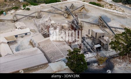 Vue aérienne d'un vaste complexe industriel, avec ses bâtiments blancs et ses bandes transporteuses labyrinthiques contrastant avec le vent environnant Banque D'Images